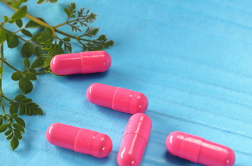 Herbal medicine in capsules with green leaf herbs