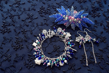 Jewelry set. Bracelet with pendants and beads made of glass and metal. Textured background with jewelry. Earrings and beaded flower.