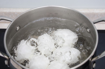 White chicken eggs boil in a saucepan