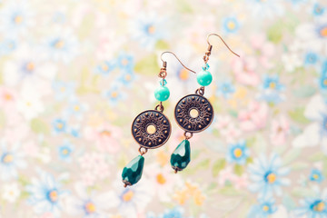 Fototapeta na wymiar Metal pendants and beads earrings. Long dangling earrings. Macro photo of jewelry on the textured background.