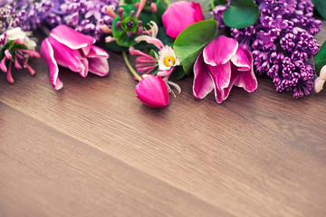 Beautiful flowers lying on a wooden background. A spring gift to women. Flowers for his girlfriend. Fresh flowers. Lilacs and tulips bouquet on a wooden background