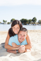 Young happy couple lying on sand beach together on seashore