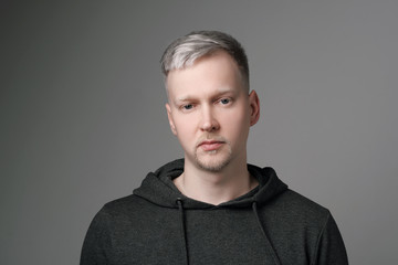Young man with gray hair in casual clothes on white and gray background. Portrait in the studio. Creative hair coloring.