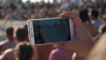 Closeup man hand holds a mobile shoot with phone camera an event in public place