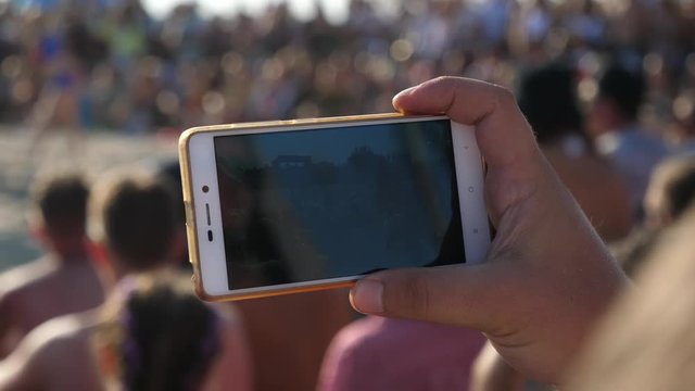 Closeup man hand holds a mobile shoot with phone camera an event in public place