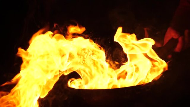 Chef cooking food in the wok pan tossing it up in burning flame at night slow motion