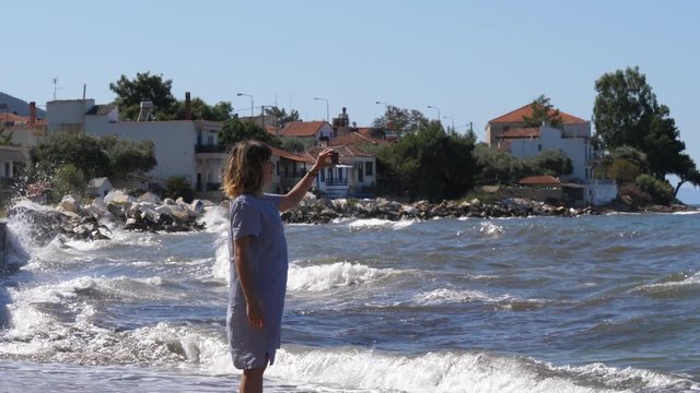 Sea waves splashing in Thassos Greece bay young woman take picture via mobile phone of her travel leisure