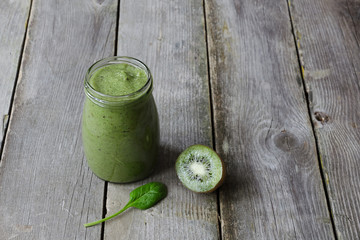 Green smoothie with kiwi and leaf of spinach on wooden background