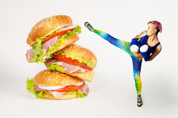 A young girl kicks a hamburger. The concept is the fight against unhealthy food.