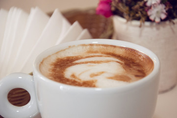 Appetizing coffee in a white cup on a table indoors, close-up