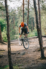 front view of male extreme cyclist in protective helmet doing stunt on mountain bicycle in forest