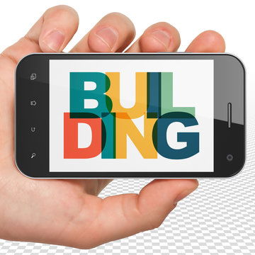 Construction concept: Hand Holding Smartphone with Painted multicolor text Building on display, 3D rendering