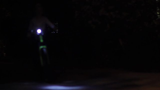 boy at night riding a bike,At night on the street, the boy rides a bicycle along the road with a lantern