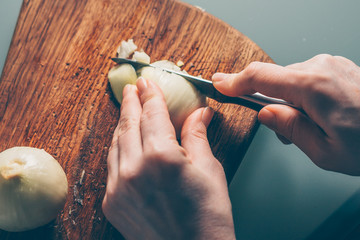 The cook cuts the onion on a cutting board