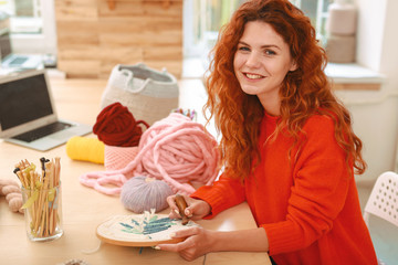 Freelancer on break. Happy beaming freelancer embroidering nice floral picture during her lunch...