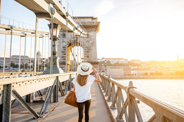 Young woman traveler walking on the famous Chain bridge during the sunset in budapest, Hungary