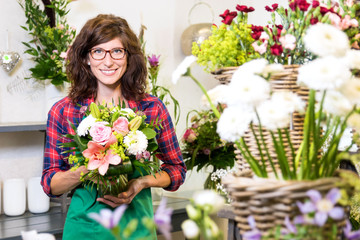 Freundlich lächelnde Floristin mit frisch gebundenem Blumenstrauss