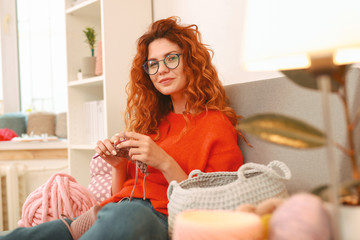 Amicable girl. Amicable beautiful girl with long wavy ginger hair sitting near big window while...