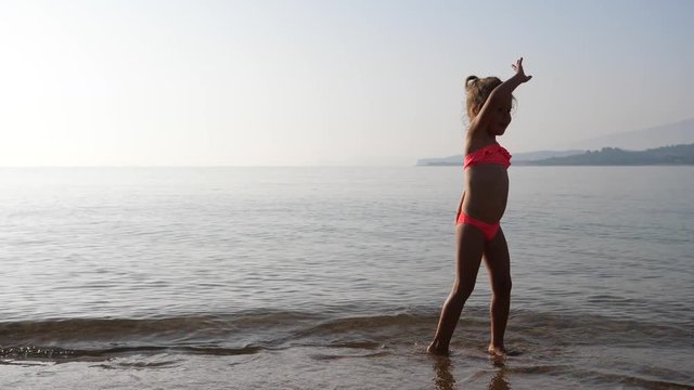Happy summer leisure kid girl play dance in shallow water in Greece thassos beach
