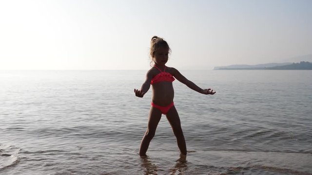 Happy summer leisure kid girl play dance in shallow water in Greece thassos beach
