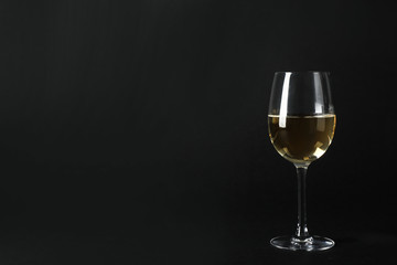 Glass of expensive white wine on dark background