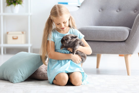 Little girl with adorable rabbit indoors