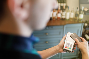 Hand of customer paying with contactless credit card with NFC technology.