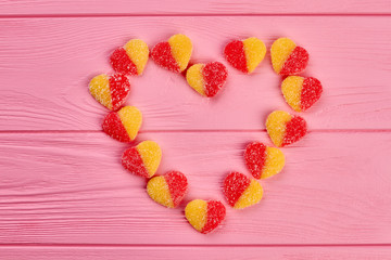 Heart shape from jelly candies. Sweet heart from colorful candies on pink wooden background. Creative greeting with Valentines holiday. Valentines Day tasty decorations.