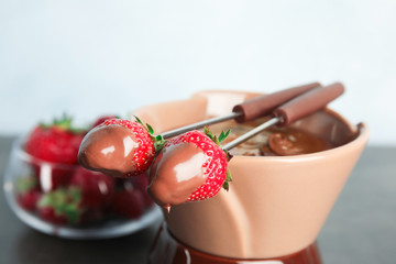 Ripe strawberries dipped into chocolate fondue, closeup