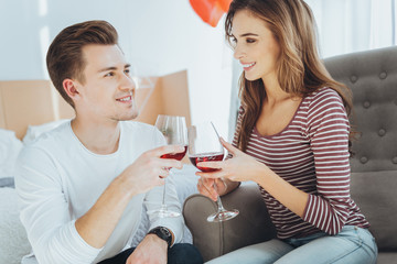 Our anniversary. Nice married couple clinking glasses with wine while celebrating their anniversary