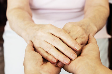 Fototapeta premium Mature female in elderly care facility gets help from hospital personnel nurse. Senior woman w/ aged wrinkled skin & care giver, hands close up. Grand mother everyday life. Background, copy space.