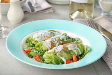 Plate with stuffed cabbage leaves and sour cream on table