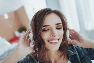 Fototapeta premium Music lover. Portrait of a cheerful young woman listening to music while wearing headphones