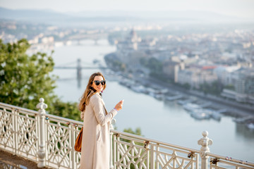 Young woman photographing beautiful morning view on Budapest city from the Gellert hill in Hungary