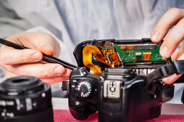 Naklejka premium Close up hands of a service worker repairing digital camera.