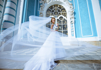 Beauty bride in bridal gown with bouquet and lace veil in the nature