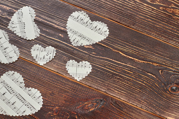 Paper hearts with musical notes on wood. Paper heart shaped figures with music notes on brown...