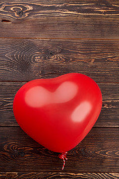 Heart shaped balloon for Birthday party. Red balloon on textured wooden background, copy space.