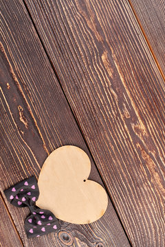 Valentines Day decoration on wooden background. Plywood heart and bow tie, top view.