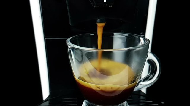 coffee moka machine with hot italian coffee arabica starting go out with foam in slow motion, using a coffee mocha maker machine, breakfast starting concept with a transparent cup of coffee