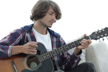 Handsome man playing on the guitar on the couch at home