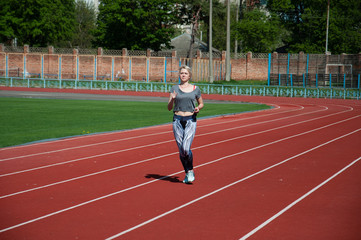 Fototapeta premium Kobieta sport działa lekkoatletyka działa na bieżni na stadionie w słoneczny poranek w lecie