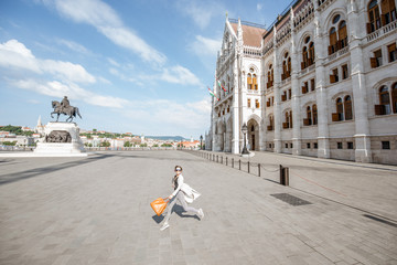 Woman walking on the square near the famous Parliament building during the mornign light in...
