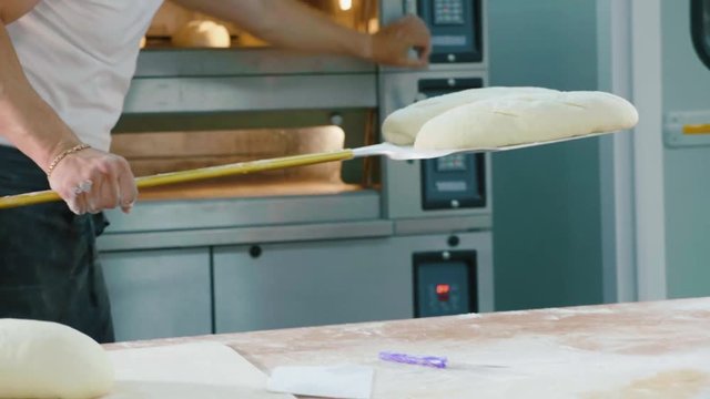 Professional Baker Puts Raw Bread Into The Oven In A Commercial Kitchen