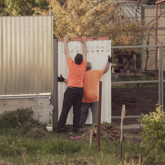Workers install the fence with a metal profile