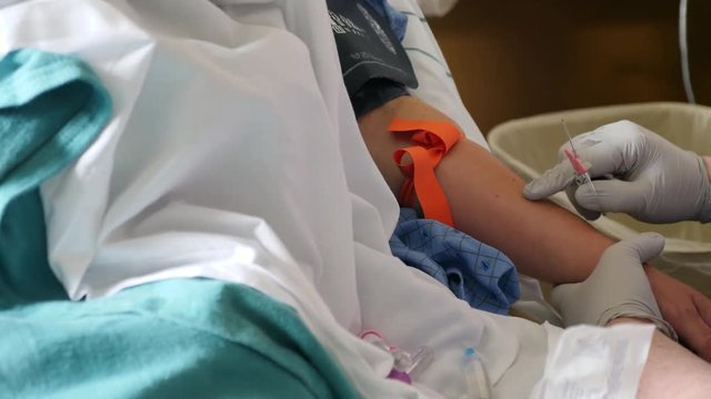 A nurse putting an IV into a womans arm at the hospital
