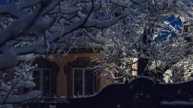 Beautiful winter greeting card with trees and house cover snow, street light and slow motion snowfall. Winter fairytale night.