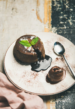 Hot chocolate souffle dessert cake with liquid filling and chocolate ice cream over rustic wooden painted background