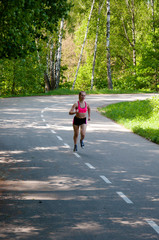 Beautiful smiling woman running in the park in the morning. Fitness girl running in the park. Running woman. Female Runner Jogging during Outdoor Workout in a Park. Beautiful fit Girl.