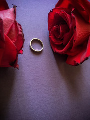 gold ring and two rose on the violet floor